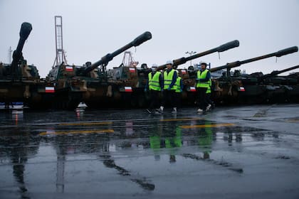 Una delegación militar surcoreana camina junto a los cañones Thunder K9 en el puerto de la armada polaca en Gdynia, Polonia