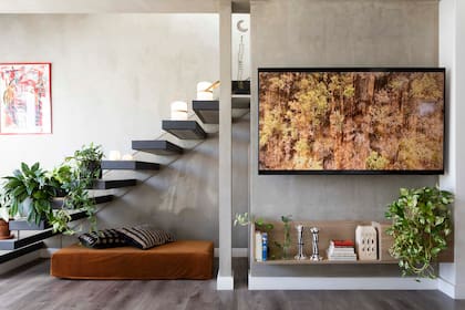 Una delgada columna de placa de yeso ayuda a definir el sector de la TV. La escalera tiene peldaños de hormigón con terminación en laca mate.