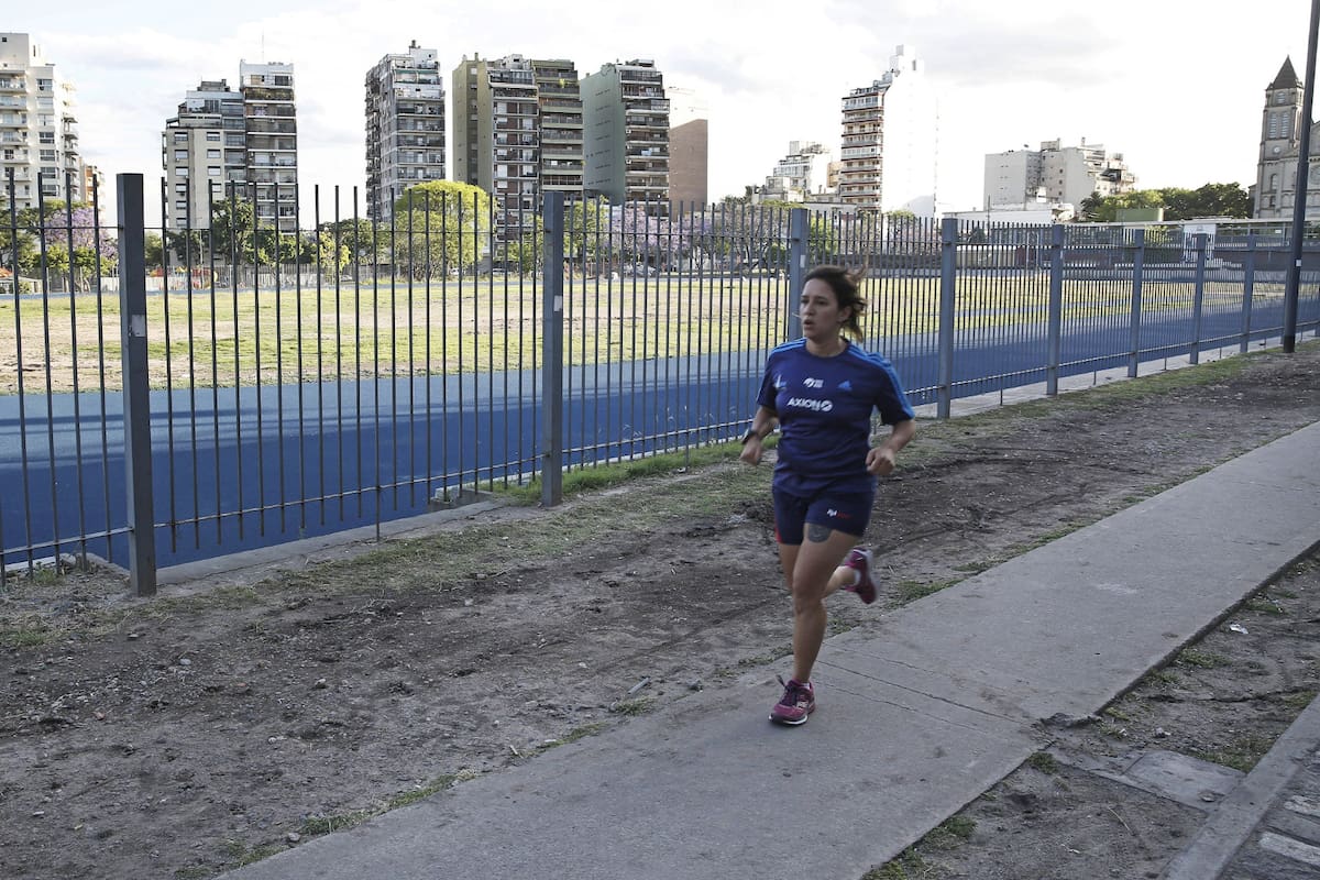 Una deportista amateur corre por el perímetro del Parque Chacabuco mientras aguarda la pista sintética