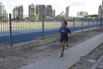 Una deportista amateur corre por el perímetro del Parque Chacabuco mientras aguarda la pista sintética