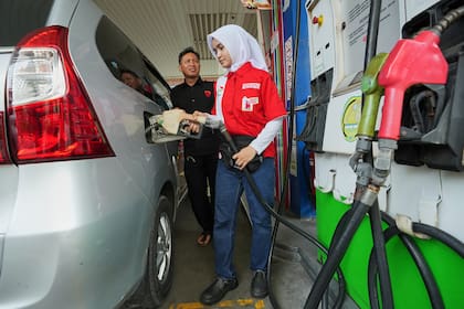 Una empleada llena el depósito de un auto en una gasolinera de Yakarta, Indonesia, el martes de marz