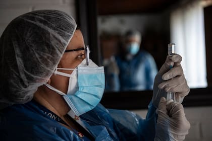 Una enfermera se prepara para inocular a una mujer con contra el Covid-19 en el municipio de La Florida en Santiago, el 01 de marzo de 2021