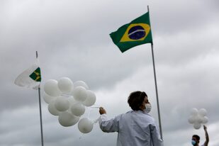 Una enfermera suelta globos blancos que representan vidas que podrían haberse salvado con la vacunación contra el coronavirus, afuera del Congreso brasileño, en Brasilia