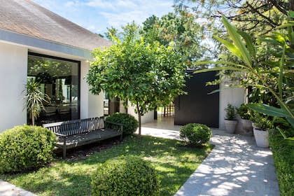 Una entrada lateral atraviesa el jardín hasta el portón corredizo que desemboca directamente en la zona de la parrilla.