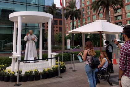 Varias personas toman fotos de la estatua del Papa