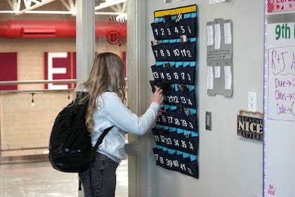 Una estudiante de noveno grado coloca su teléfono en un organizador mientras entra a un aula de la Escuela Secundaria Delta, el viernes 23 de febrero de 2024, en Delta, Utah. (AP Foto/Rick Bowmer)