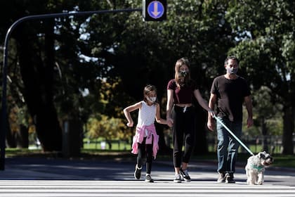 Una familia con barbijo cruza la calle después de que las autoridades permitieron que los niños salgan durante una hora con fines recreativos de acuerdo con el número de identificación de sus padres, en medio del bloqueo impuesto contra la propagación del nuevo coronavirus en Buenos Aires el 16 de m