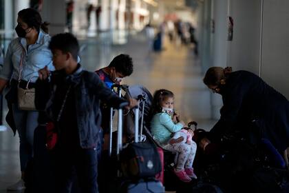 Una familia que regresa a casa a Panamá después de pasar tres semanas en Estados Unidos llega al aeropuerto internacional de Miami antes de su vuelo, el lunes 27 de diciembre de 2021. (AP Foto/Rebecca Blackwell)