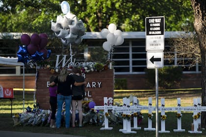 Una familia rinde homenaje frente a las cruces que llevan los nombres de las víctimas en la escuela primaria Robb en Uvalde, Texas.