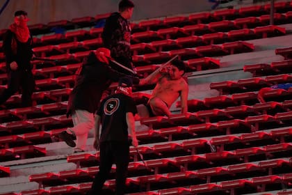 Una fanático de la Universidad de Chile (centro) es agredido por hinchas de Independiente de Argentina durante el partido por los octavos de final de la Copa Sudamericana, el miércoles 20 de agosto de 2025, en Avellaneda, Argentina. (AP Foto/Gustavo Garello)