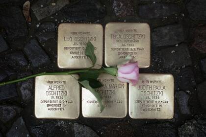 Una flor cruza las 'Stolpersteine', o escollos, que conmemoran a personas deportadas y asesinadas por los nazis frente a un edificio residencial en Berlín, mártes 9 de noviembre de 2021, el 83er aniversario de la Kristallnacht, la noche de los cristales rotos, un pogromo antijudío de los nazis. (APFoto/Markus Schreiber)