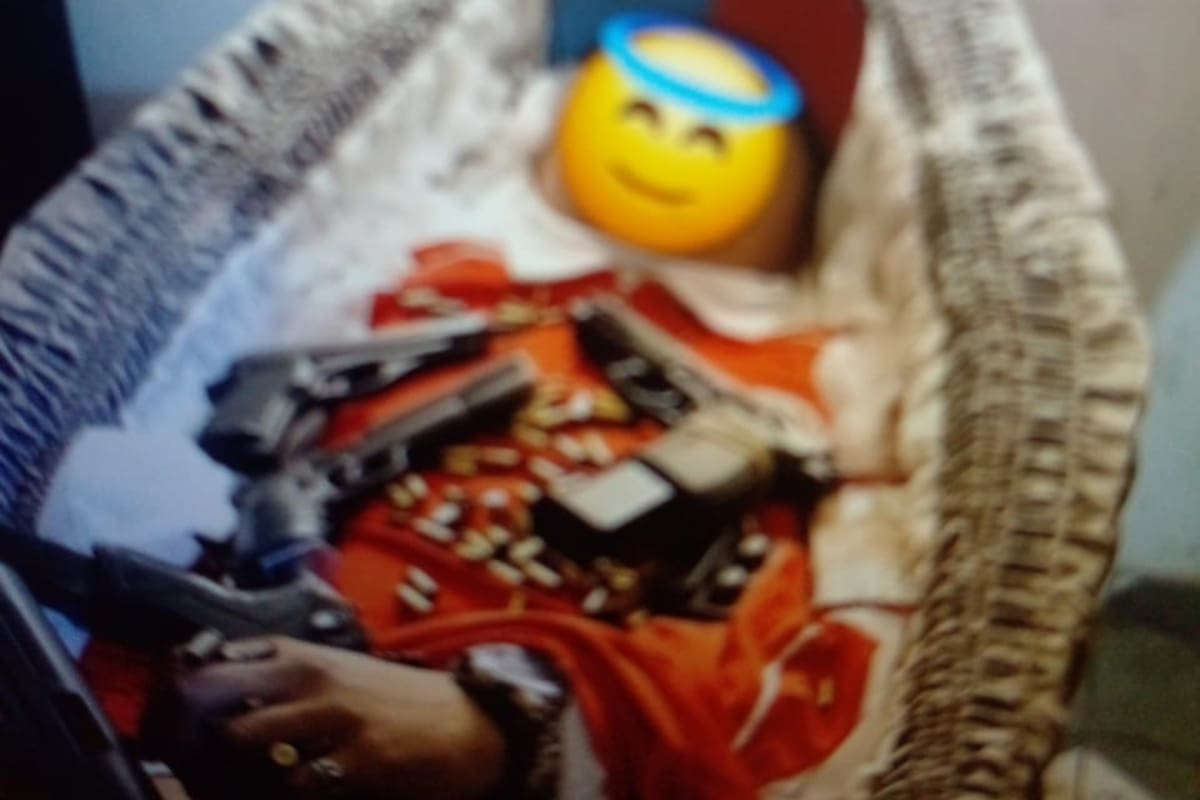 Una foto del motochorro muerto dentro del ataúd empuñando un arma y con otras armas sobre el cuerpo