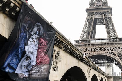 Una foto tomada en París el 16 de diciembre de 2020 muestra un letrero que representa la bandera francesa y que dice durante la pandemia, ocurre otra tragedia