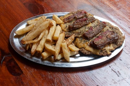 Una guarnición de papas fritas acompañan una "milanesa" vegana con chedar