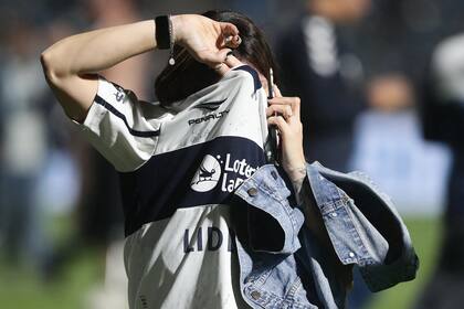 Una hincha de Gimnasia y Esgrima se protege el rostro y busca la salida