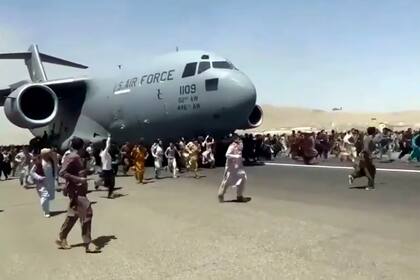 Una imagen que ya se volvió símbolo: el 16 de agosto de 2021, cientos de personas corren al lado de un avión de carga C-17 de la Fuerzas Aérea de Estados Unidos que trata de despegar en la pista del aeropuerto internacional de Kabul, Afganistán