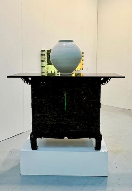 Una instalación artística contemporánea compuesta por un mueble tradicional con un jarrón de porcelana blanca. En Kiaf Seoul