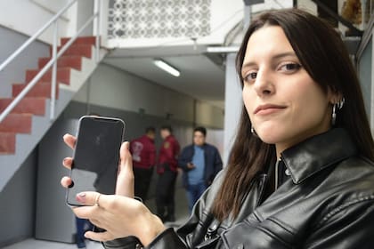 Una joven muestra el teléfono que le había sido robado y recuperó a través de la plataforma virtual con el inventario de objetos hallados en operativos de la Policía de la Ciudad