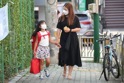 Una madre acompaña a su hija camino a una escuela primaria en Seúl el 25 de agosto de 2020