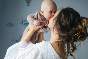 Una madre besa a su bebé recién nacido, un gesto que simboliza el amor infinito y la devoción que comienzan desde el primer instante de vida