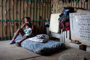 Una madre joven cuida de su hijo en su improvisada casilla en el Cementerio General del Sur, en Caracas