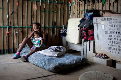 Una madre joven cuida de su hijo en su improvisada casilla en el Cementerio General del Sur, en Caracas