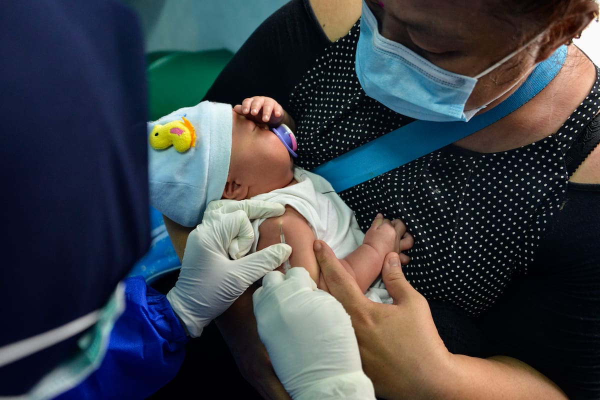 Una madre sostiene a su bebé mientras un miembro del personal médico administra la vacuna contra la tuberculosis en un centro de salud comunitario en Banda Aceh el 15 de junio de 2020
