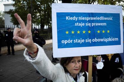 Una manifestante sostiene un cartel que dice "Cuando la injusticia se convierte en ley, la resistencia se convierte en un deber" frente al Tribunal Constitucional en Varsovia el 7 de octubre de 2021, mientras el tribunal celebra una audiencia sobre la primacía de la legislación de la UE o de Polonia. (Foto de Jaap Arriens / AFP)