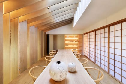Una mesa de roble francés con borde natural rodeada de sillas Hans Wegner Wishbone, también en roble, adorna el comedor “europeo”; las mamparas corredizas shoji ocultan una cocina.