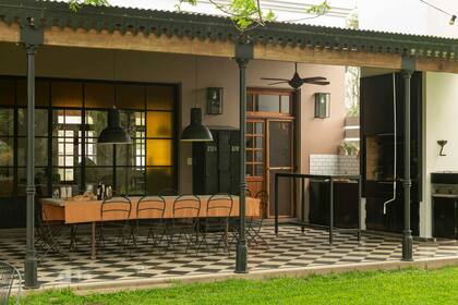 Una mesa para doce comensales con sillas quilmes se corona con galponeras XL junto al espacio de la parrilla.