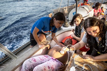 Una migrante embarazada es asistida por un equipo de rescate en aguas del Mediterráneo