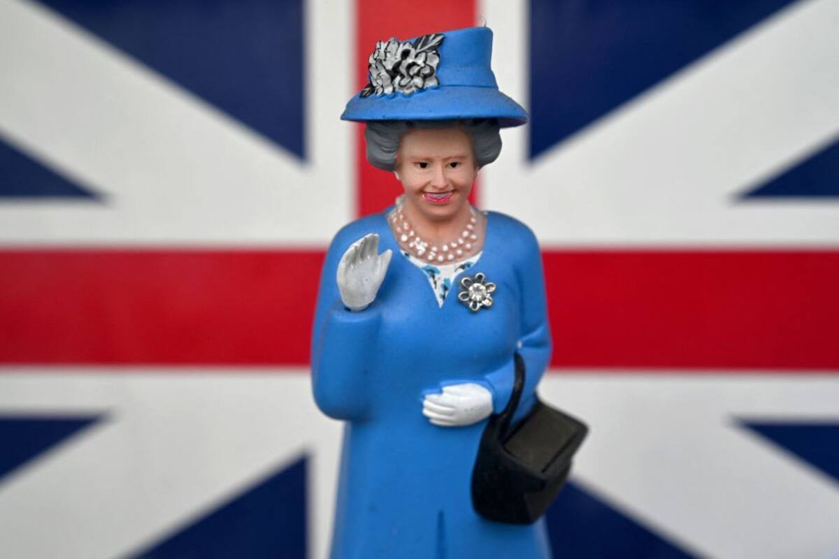 Una miniatura de la reina Isabel II, que mueve su mano impulsada por energía solar, se exhibe en la vitrina de una tienda de souvenirs en Madrid, el 25 de marzo de 2021