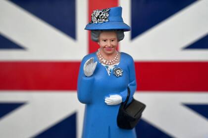 Una miniatura de la reina Isabel II, que mueve su mano impulsada por energía solar, se exhibe en la vitrina de una tienda de souvenirs en Madrid, el 25 de marzo de 2021