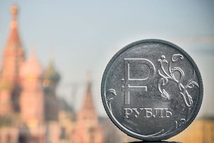 Una moneda de rublo ruso se muestra frente a la catedral de San Basilio en el centro de Moscú, el 28 de abril de 2022
