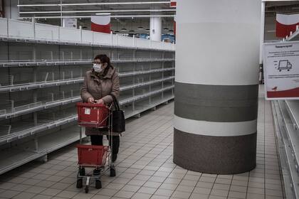 Una moscovita deambula por un supermercado de Moscú con las góndolas vacías
