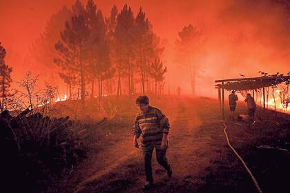 Una mujer abandona, ayer, su propiedad devorada por el fuego en Amendoa