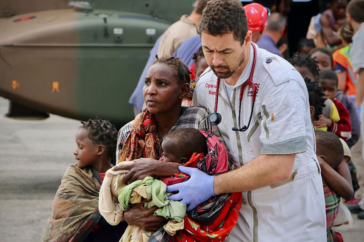 Una mujer abraza a su hijo mientras la asiste un rescatista en el aeropuerto de Beira, Mozambique
