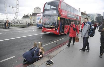 Una mujer asiste a una persona herida en el puente de Westminster