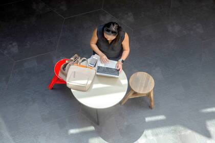 Una mujer atiende el teléfono y utiliza un notebook en una cafetería de Sídney, Australia, el último país que acaba de incorporar el derecho a la desconexión digital