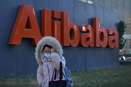 Una mujer camina delante de las oficinas del gigante de comercio en la internet Alibaba en Beijing el 13 de diciembre del 2021.  (AP Photo/Andy Wong)