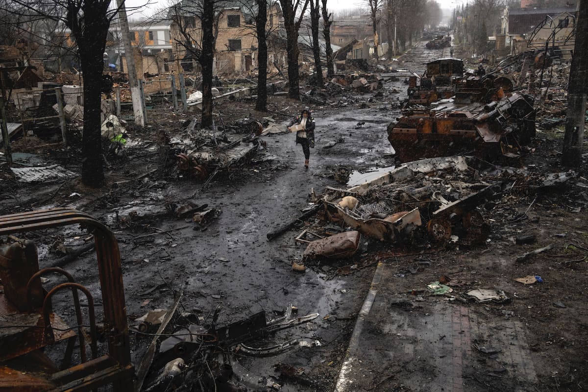 Una mujer camina entre tanques rusos destruidos en Bucha, en las afueras de Kyiv, Ucrania, el sábado 2 de abril de 2022