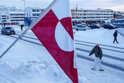 Una mujer camina frente a la bandera nacional de Groenlandia en Nuuk