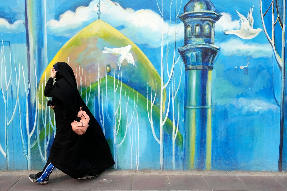 Una mujer camina frente a un mural en una mezquita del centro de Teherán (AP Foto/Vahid Salemi)