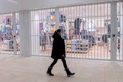 Una mujer camina frente a una tienda cerrada en un centro comercia, el domingo 2 de enero de 2022, en Montreal. (Graham Hughes /The Canadian Press via AP)