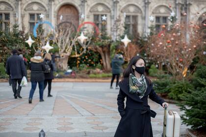 Una mujer camina junto al Ayuntamiento de Parí el 8 de diciembre del 2021. Las autoridades en Francia quieren acelerar las vacunaciones contra el coronavirus antes de la Navidad, en momentos en que aumentan las infecciones y más personas con COVID-19 buscan atención médica. (AP Foto/Rafael Yaghobzadeh)