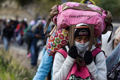 Una mujer carga sus cosas en medio de la caravana que camina hacia Perú por la autopista Panamericana en Tulcan, Ecuador, tras cruzar Colombia