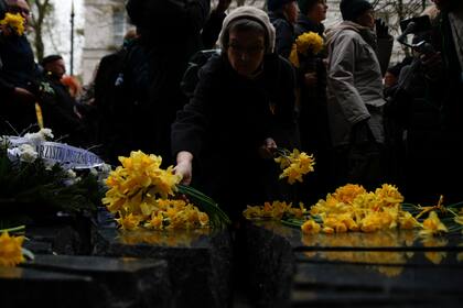 Una mujer coloca flores amarillas en el Monumento a Szmul Zygielbojm durante el 80mo aniversario del levantamiento del ghetto de Varsovia, el miércoles 19 de abril de 2023, en Varsovia, Polonia. (AP Foto/Michal Dyjuk)