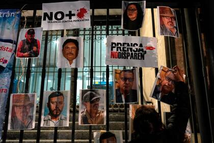 Una mujer coloca fotos de reporteros muertos durante una protesta nacional por el asesinato de Lourdes Maldonado y del fotógrafo independiente Margarito Martínez, en la Ciudad de México, el 25 de enero de 2022.