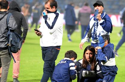 Una mujer con dos niños se protegen de los gases lacrimógenos en la cancha de juego