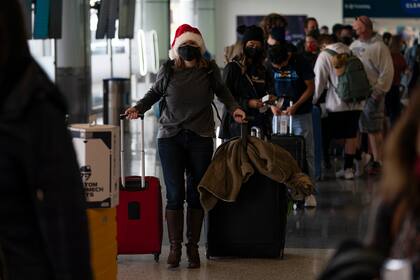 Una mujer, con gorro de Papá Noel, espera a facturar para su vuelo a Washington en el Aeropuerto Internacional de Los Ángeles, el 20 de diciembre de 2021.